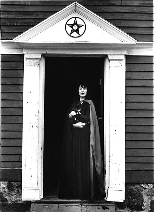 Laurie Cabot stands in front of an open doorway.