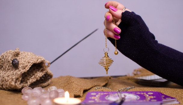 A golden pendulum over divination cards.