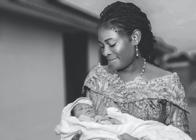 A black woman is smiling while holding her baby.